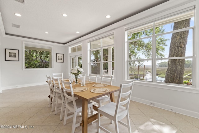 dining area with a water view, a tray ceiling, and light tile patterned floors