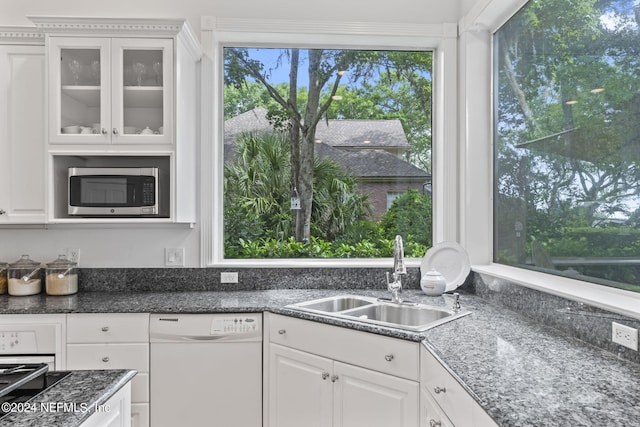 kitchen with white cabinetry, dark stone counters, dishwasher, and sink