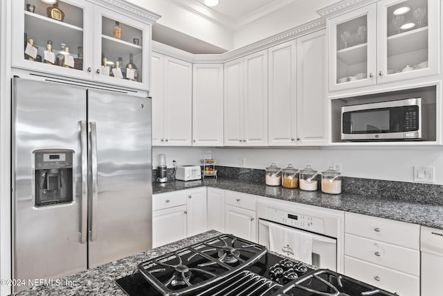 kitchen with stainless steel appliances, crown molding, dark stone countertops, and white cabinets