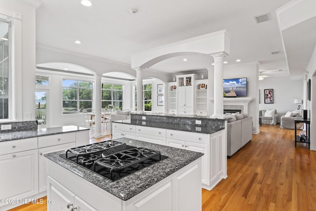 kitchen with a kitchen island, black gas cooktop, decorative columns, white cabinetry, and dark stone countertops