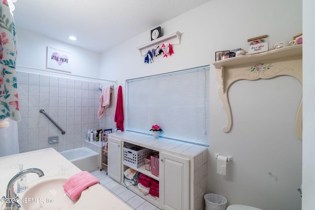 bathroom with tile patterned floors, shower / bathtub combination with curtain, and sink