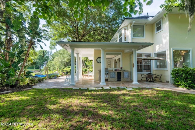 rear view of property with a patio and a lawn