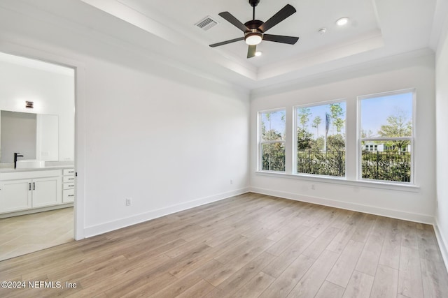 unfurnished room with a raised ceiling, light hardwood / wood-style flooring, and ceiling fan