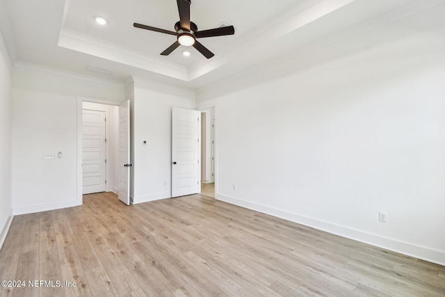 unfurnished bedroom featuring light wood-type flooring, a tray ceiling, and ceiling fan