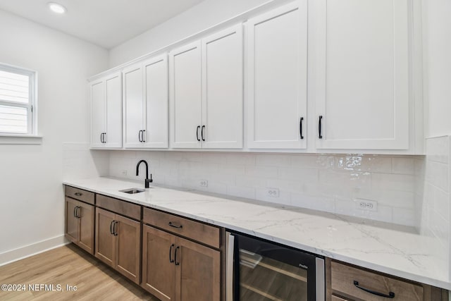 bar featuring white cabinets, sink, wine cooler, and light hardwood / wood-style flooring