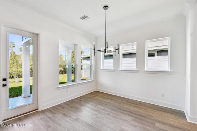 unfurnished dining area with crown molding, light hardwood / wood-style floors, and an inviting chandelier