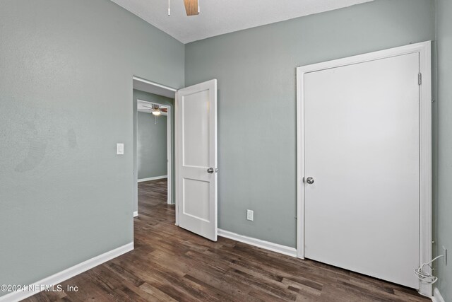 unfurnished bedroom with ceiling fan and dark wood-type flooring