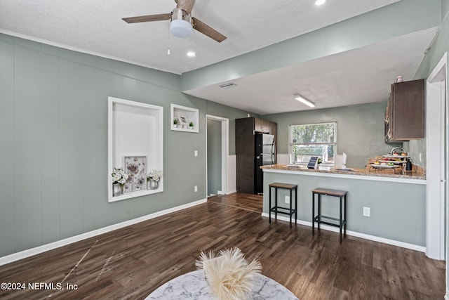 kitchen with ceiling fan, a kitchen breakfast bar, dark hardwood / wood-style floors, kitchen peninsula, and fridge