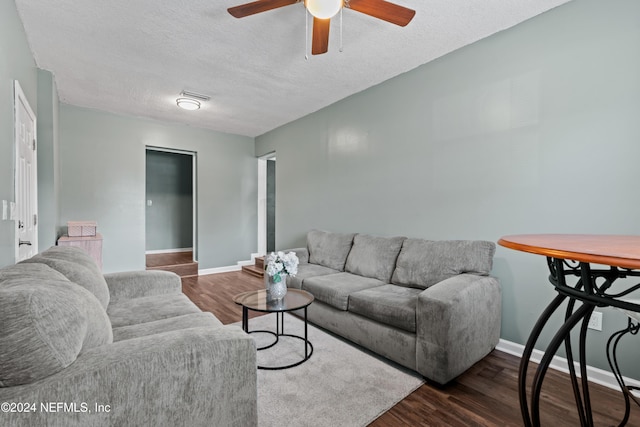 living room with dark hardwood / wood-style floors, ceiling fan, and a textured ceiling