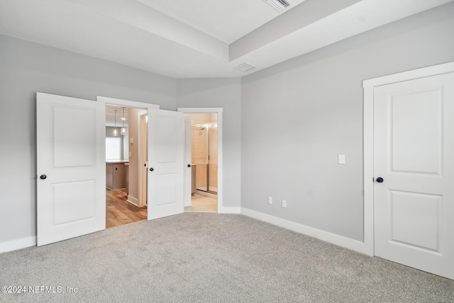 unfurnished bedroom with light colored carpet and ensuite bath