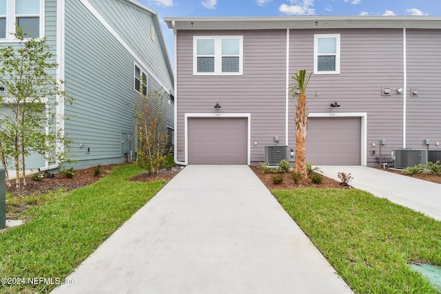 view of front of home featuring a garage, a front lawn, and central air condition unit