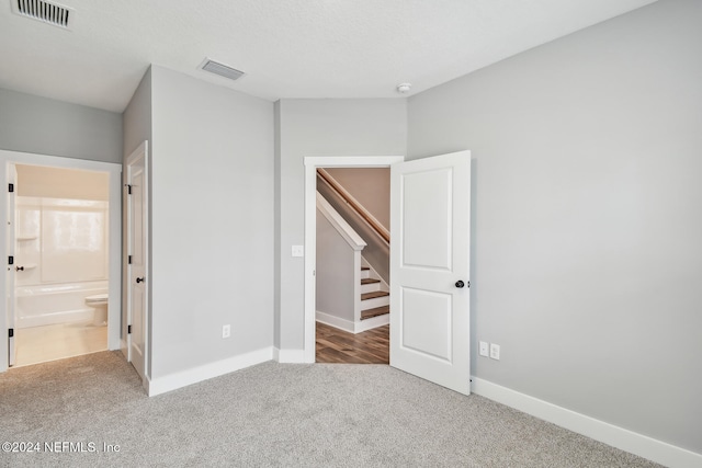 unfurnished bedroom featuring ensuite bath and carpet floors