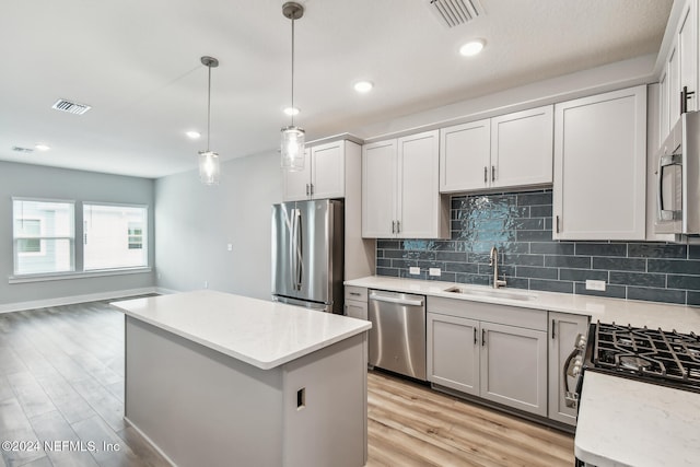 kitchen featuring sink, a center island, hanging light fixtures, light hardwood / wood-style flooring, and appliances with stainless steel finishes