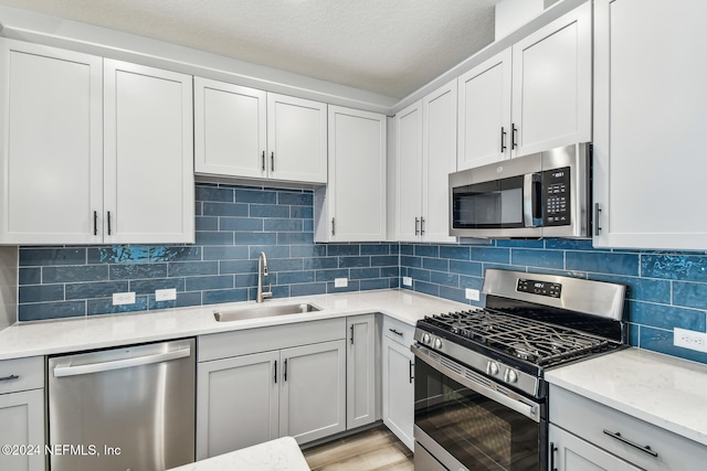 kitchen with white cabinetry, sink, backsplash, and appliances with stainless steel finishes