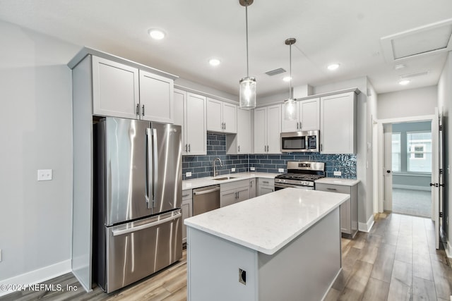 kitchen with pendant lighting, sink, appliances with stainless steel finishes, tasteful backsplash, and a kitchen island