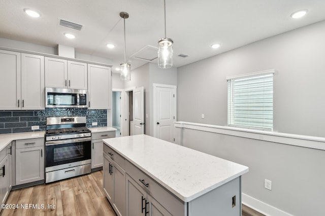 kitchen featuring a kitchen island, appliances with stainless steel finishes, pendant lighting, and decorative backsplash