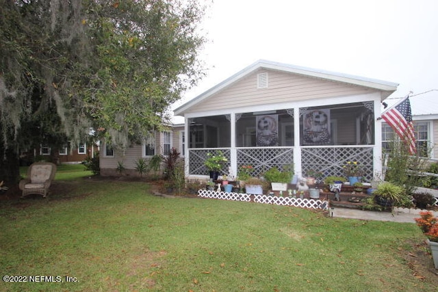 back of property with a sunroom and a lawn