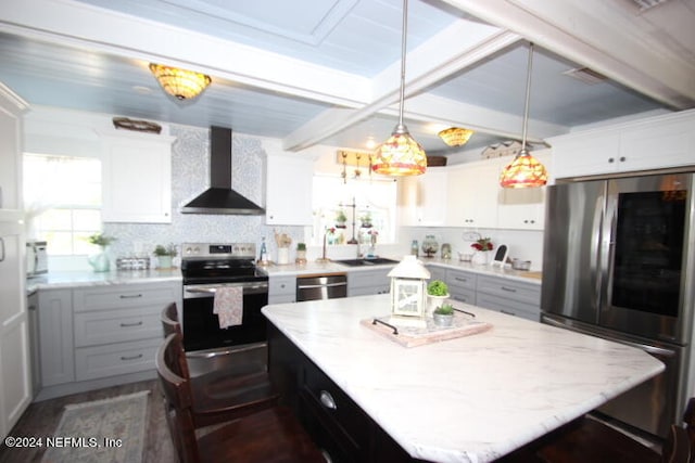 kitchen with decorative light fixtures, a kitchen island, wall chimney exhaust hood, white cabinets, and appliances with stainless steel finishes