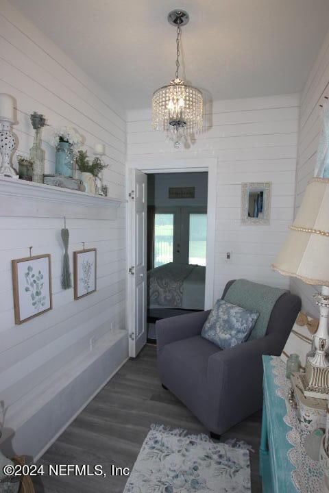 living room with a notable chandelier, french doors, wooden walls, and dark hardwood / wood-style flooring