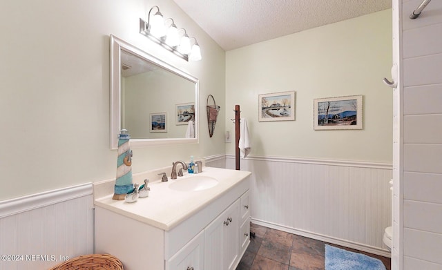 bathroom with toilet, vanity, and a textured ceiling