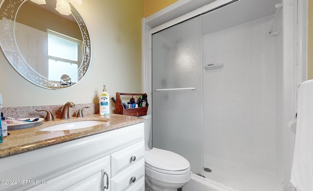 bathroom featuring a shower with shower door, toilet, and vanity