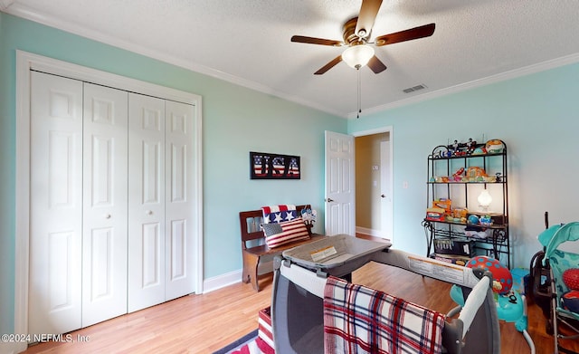 office space with a textured ceiling, ceiling fan, crown molding, and light wood-type flooring