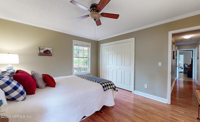 bedroom with ceiling fan, ornamental molding, a closet, and light hardwood / wood-style floors