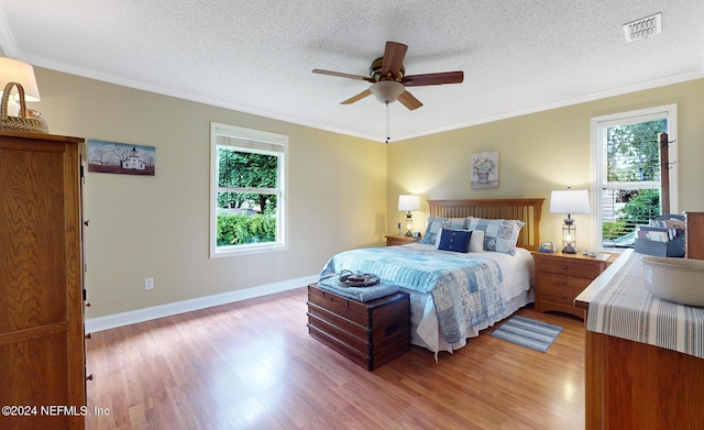 bedroom with ceiling fan, crown molding, and light hardwood / wood-style flooring