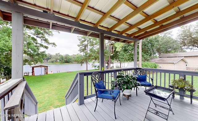 wooden deck with a water view, an outdoor fire pit, and a lawn