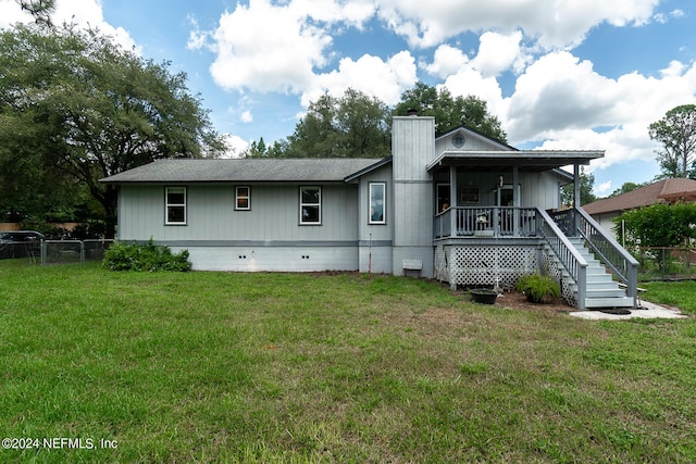 rear view of house featuring a lawn and covered porch