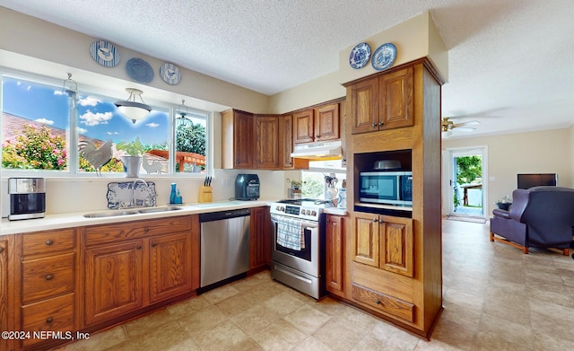 kitchen featuring a wealth of natural light, sink, stainless steel appliances, and a textured ceiling