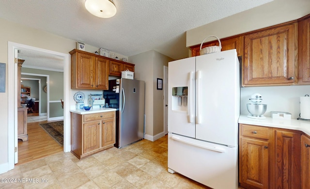 kitchen with a textured ceiling, crown molding, white refrigerator with ice dispenser, and stainless steel fridge