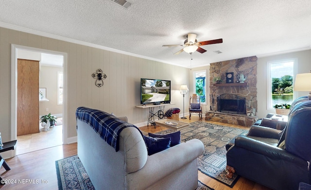 living room with a textured ceiling, light hardwood / wood-style flooring, ornamental molding, and a fireplace