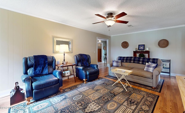 living room with hardwood / wood-style flooring, a textured ceiling, crown molding, and ceiling fan