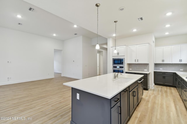 kitchen featuring backsplash, a kitchen island with sink, light hardwood / wood-style flooring, white cabinetry, and stainless steel appliances