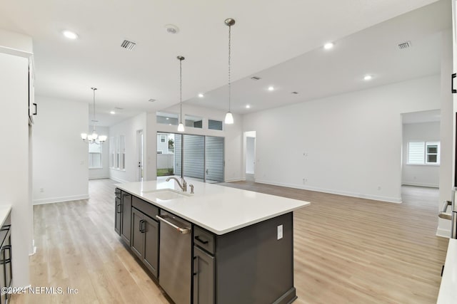 kitchen featuring dishwasher, a center island with sink, sink, light wood-type flooring, and decorative light fixtures