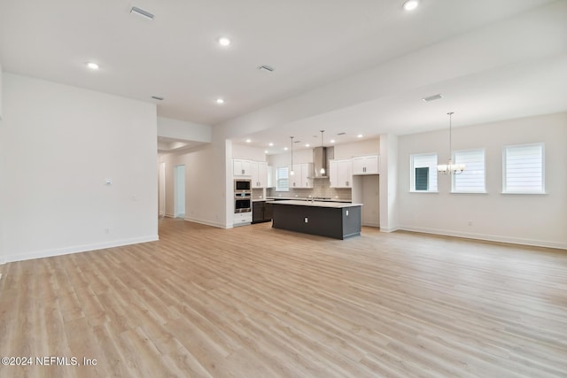 unfurnished living room featuring light hardwood / wood-style floors and a notable chandelier