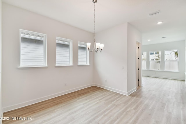 spare room featuring light hardwood / wood-style flooring and an inviting chandelier