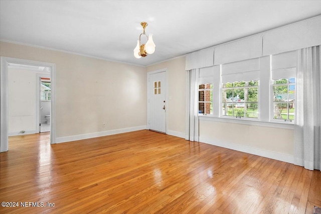 empty room with light hardwood / wood-style floors and crown molding