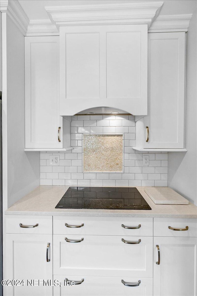 kitchen featuring backsplash, white cabinetry, black electric cooktop, and ornamental molding