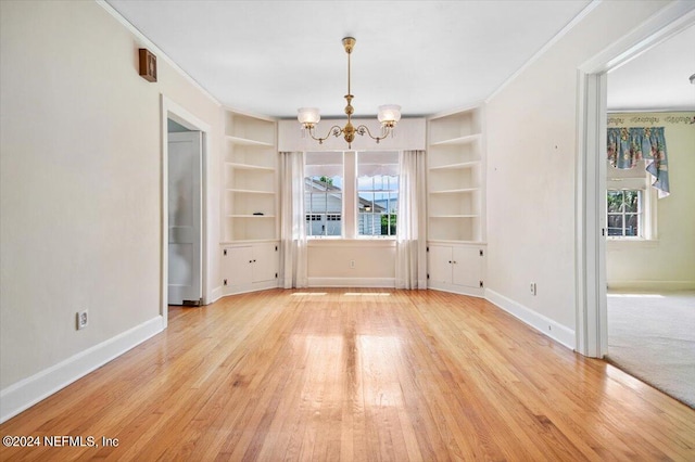 empty room featuring built in features, plenty of natural light, and light hardwood / wood-style flooring