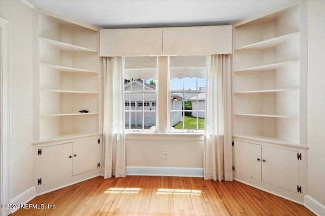 empty room with built in features and light wood-type flooring