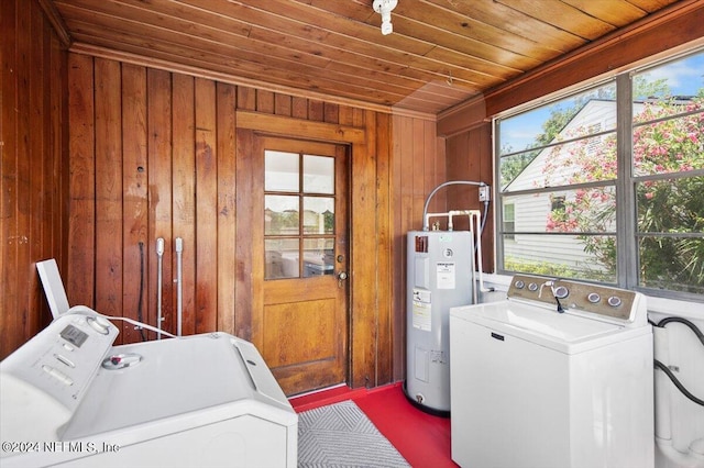 clothes washing area with washing machine and clothes dryer, wood walls, water heater, and wooden ceiling