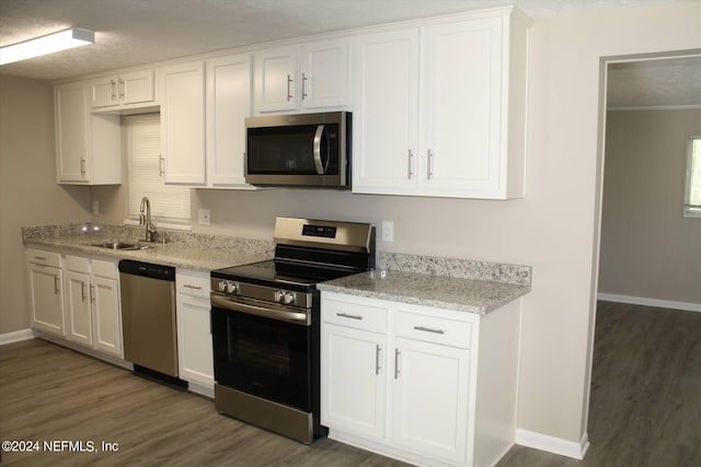 kitchen featuring light stone countertops, dark wood-type flooring, stainless steel appliances, white cabinets, and sink