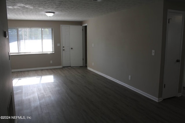 empty room featuring dark wood-type flooring and a textured ceiling