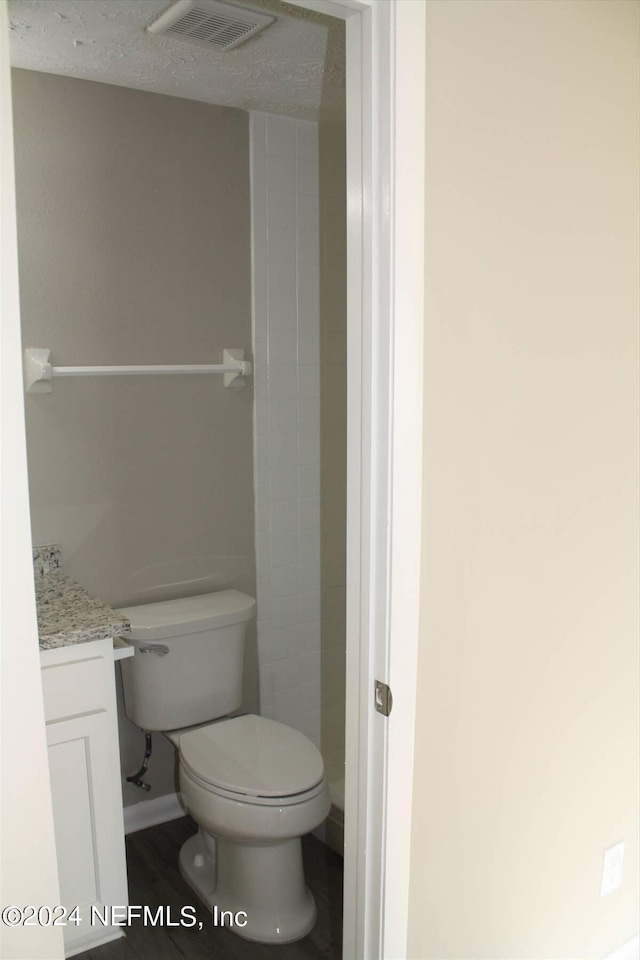 bathroom featuring a textured ceiling, toilet, and vanity