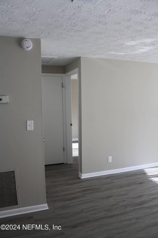 spare room featuring a textured ceiling and dark hardwood / wood-style floors