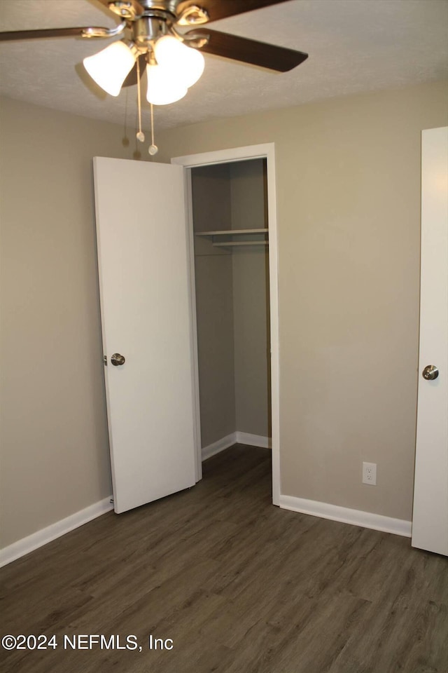 unfurnished bedroom featuring dark hardwood / wood-style floors, ceiling fan, and a closet