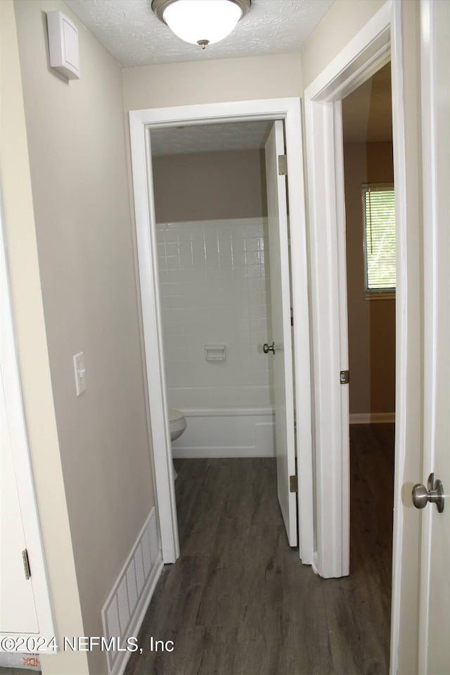 hall with dark hardwood / wood-style flooring and a textured ceiling