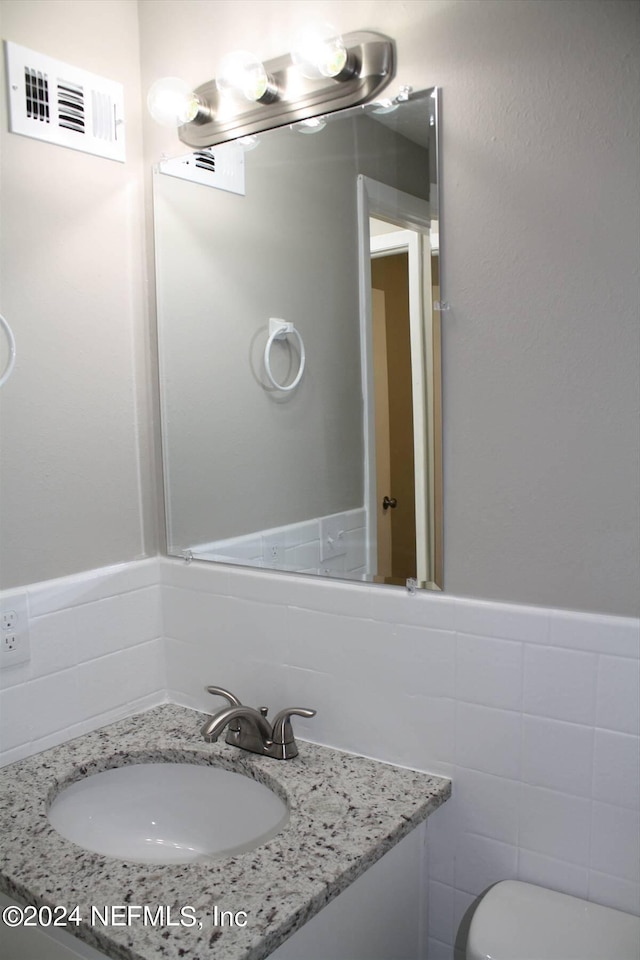 bathroom with tile walls, toilet, and vanity